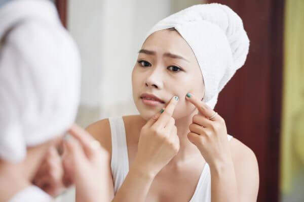 Asian Woman Popping Pimples In Mirror